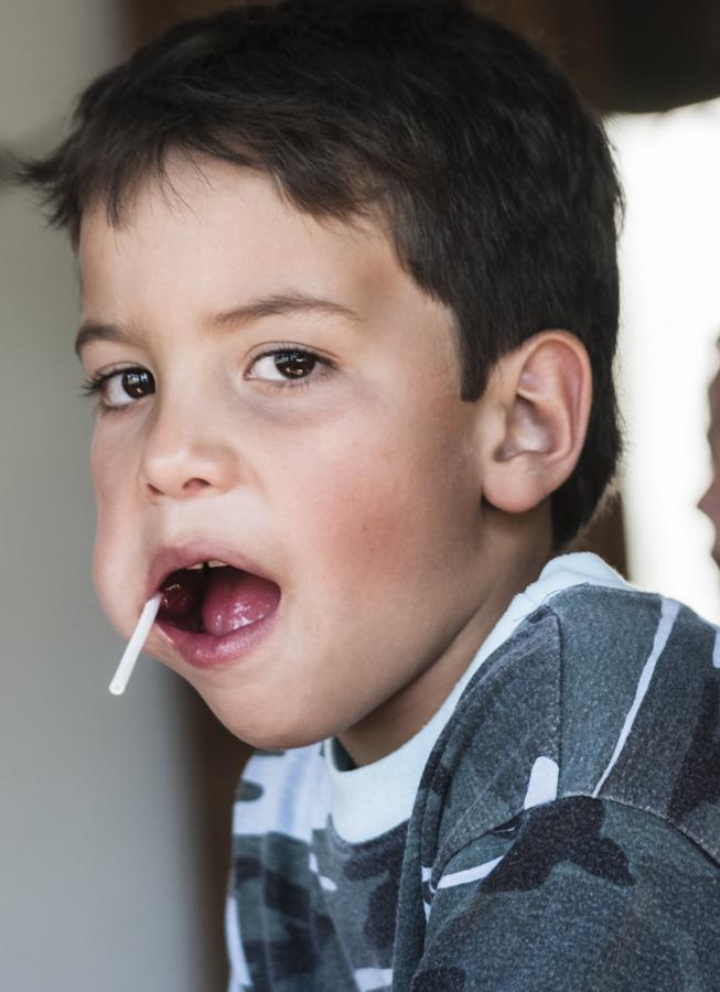 Niño con un bombón en la boca