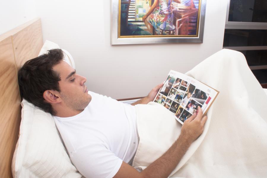 Hombre Acostado en una Cama Leyendo una Revista